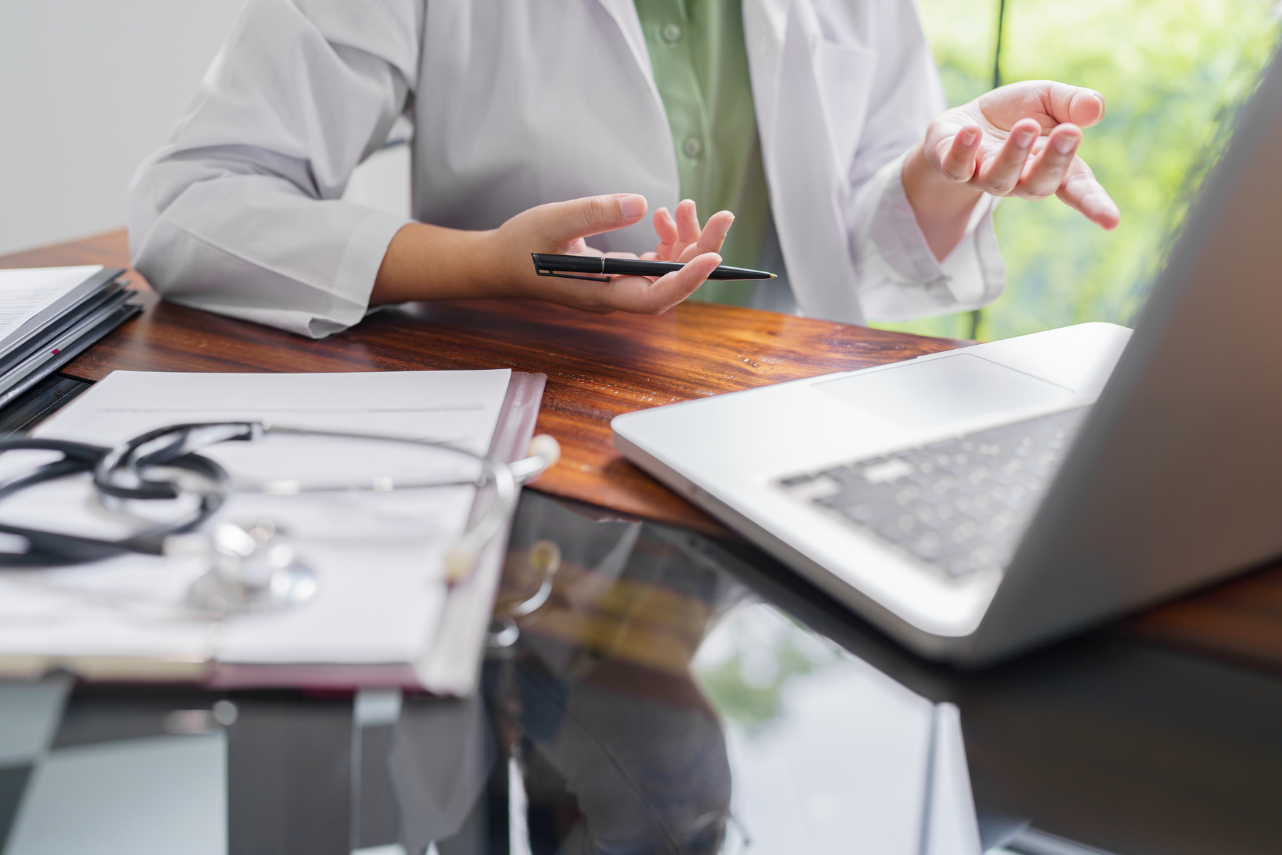 a health professional sitting at a desk with a laptop and patient chart